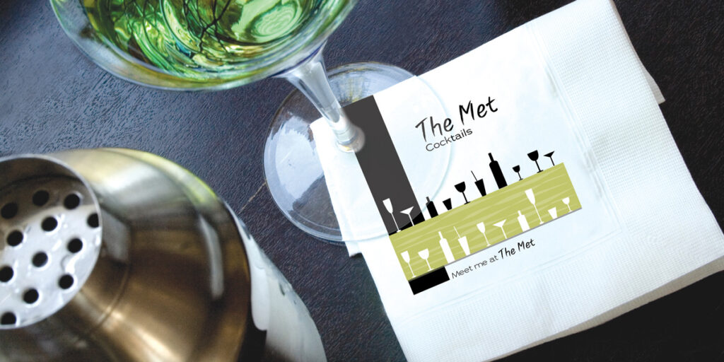 Custom cocktail napkins on a Restaurant bar counter showing cocktail setting with custom restaurant and bar napkins. Custom printed personalized cocktail
